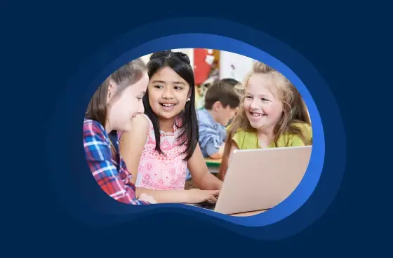Three students smiling with a laptop in front of them